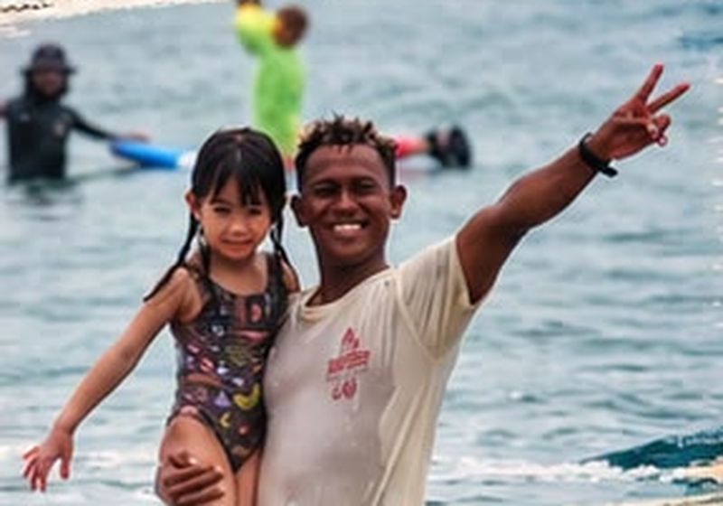 Happy kid after a surf lesson with her coach